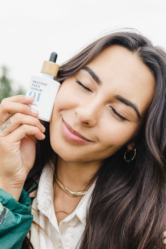Woman Holding CBD Restore Face Serum and Smiling