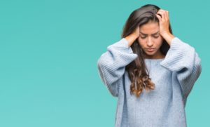 Stressed woman in sweater in front of blue background
